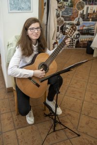 Régi Emese gitározik a kiállításmegnyitón.