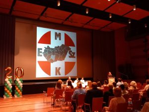 A jubileumi ünnepségre feldíszített konferenciaterem - a kép előterében a közönség, a szónoki pulpitusnál Dr. Pátri Eszter vármegyei tiszti főorvos köszöntőt mond, az elnöki asztalnál Dr. Hirdi Henriett, a MESZK alelnöke, Kis Zoltán a szekszárdi kórház-főigazgatója és Munk Jánosné a MESZK Tolna vármegyei területi elnöke ülnek.